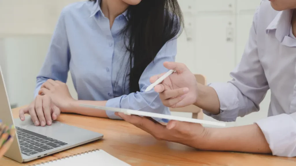 Two strata managers reviewing documents on a tablet at a desk